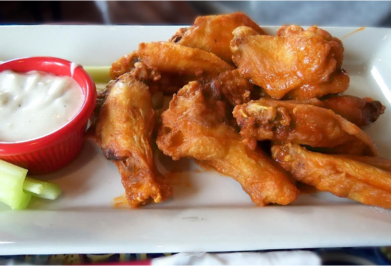 Plate of buffalo wings served with a side of celery and some ranch